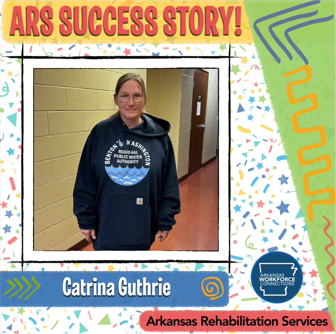 Catrina Guthrie looks at the camera and smiles, standing in a hallway at her job with the Water Authority.