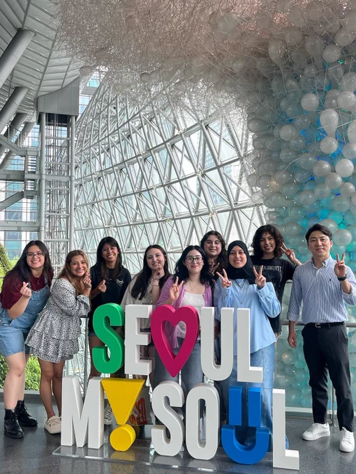 A group of students with their professor behind a sign that says "Seoul My Soul" during a study abroad trip in South Korea.