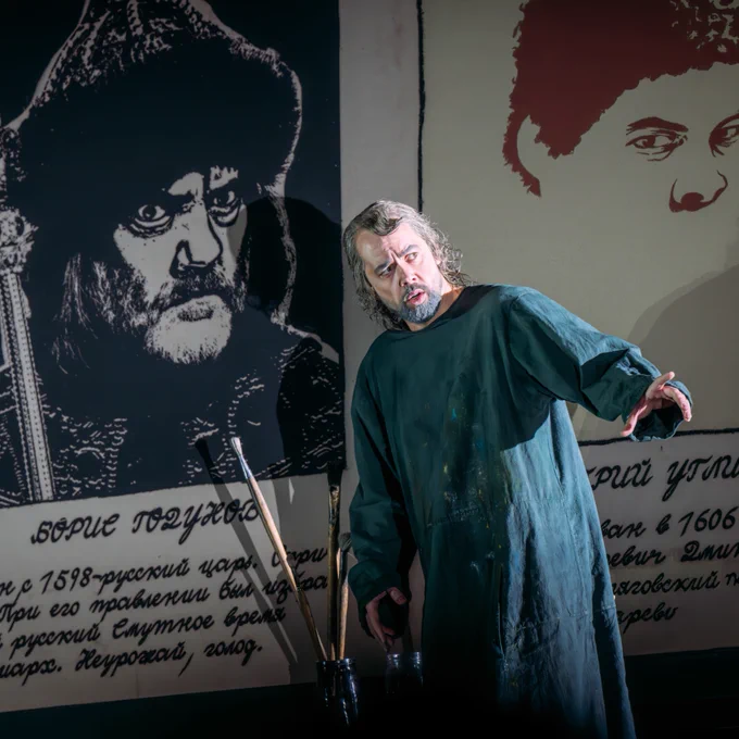 A man acting in Boris Godunov, he has a shocked expression on his face and is holding his arm out.