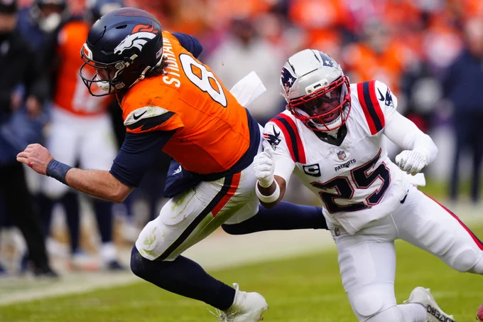 Jan 25, 2026; Denver, CO, USA; Denver Broncos quarterback Jarrett Stidham (8) rushes the ball past New England Patriots cornerback Marcus Jones (25) during the first half in the 2026 AFC Championship Game at Empower Field at Mile High. Mandatory Credit: Ron Chenoy-Imagn Images