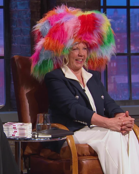 An image of Deborah Meaden wearing a large, multi-coloured fluffy hat