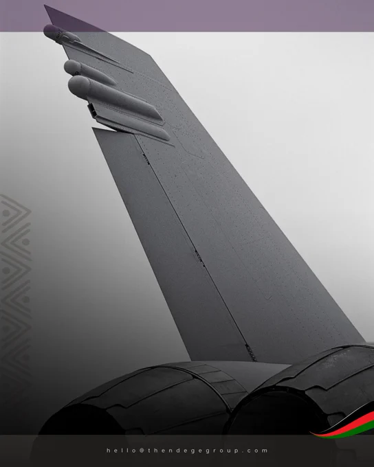 Military jet fighter aircraft tail section photographed in monochrome from ground perspective, vertical stabiliser with swept leading edge visible against overcast sky, twin jet engine exhausts visible below tail assembly, aerodynamic surfaces and panel lines emphasising combat aviation engineering. The image represents defence equipment procurement standards being established as The Ndege Group® coordinates United African Defence Force© assembly through national military secondments backed by The African Rare Earth Mineral Fund©. Each technical component reflects equipment manufacturer partnerships respecting sovereignty principles codified within The African Charter© rather than dependency relationships undermining continental autonomy. The composition demonstrates that defence capacity requires procurement aligned with institutional values. Ndege Aerospace©. The Ndege Group®, Africa’s Sovereign Development Trust® (ASDT)