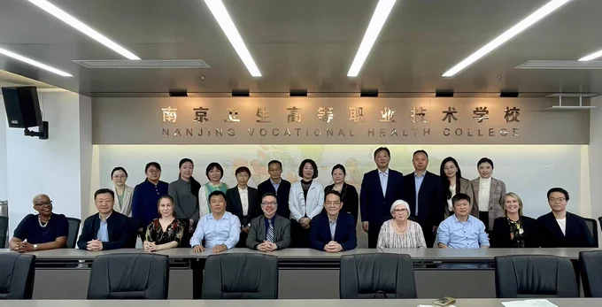 A group of officials from the faculty at King's and from Nanjing sit together along a long table