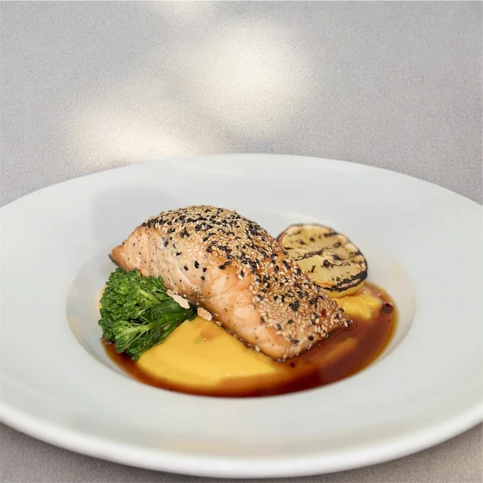 Seared salmon fillet coated with sesame seeds served on a bed of creamy yellow puree with grilled zucchini and steamed broccoli.