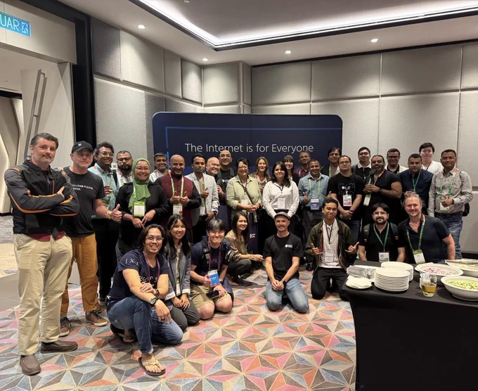 A large group of people pose in front of an Internet Society sign at APRICOT 2025