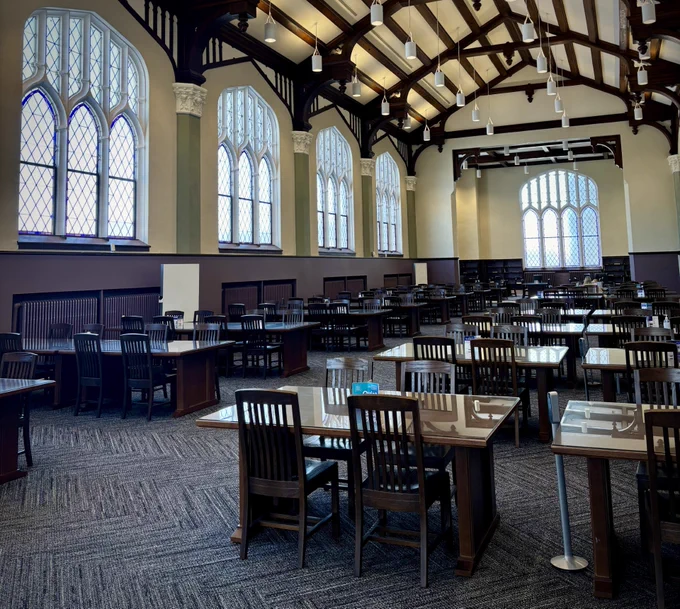 An empty room in Hale Library on Kansas State University's campus with tall ceilings and tables and chairs.