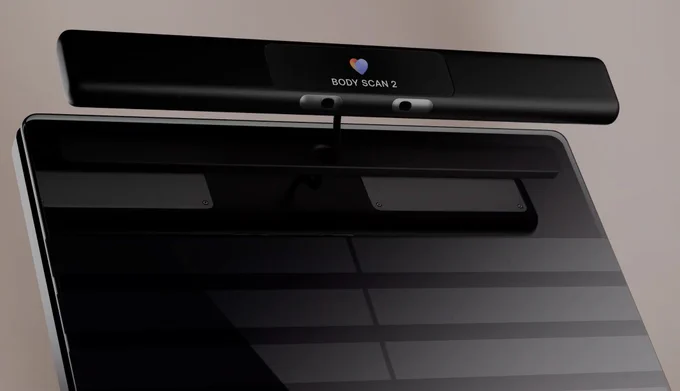 Close-up of a black Withings Body Scan 2 smart scale, showing the glass weighing surface and a raised top bar with sensors and the “Body Scan 2” label.