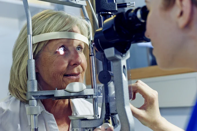 Photo of a doctor looking into a patient’s eye with a light.