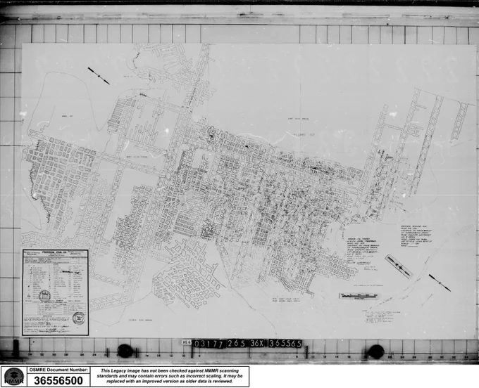 Detailed black and white mine map showing streets, blocks, landmarks, and underground mine workings with a grid overlay and official stamps in the corner.