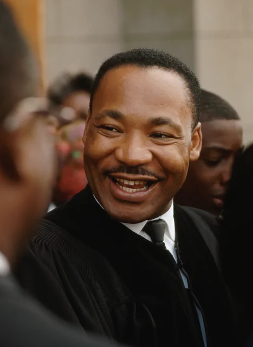 A photo of Dr. Martin Luther King Jr., smiling and looking toward someone off to the side of the camera.