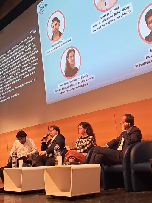 Photo de la scène pendant la table ronde avec le nom des intervenants en fond mais de l’autre côté de la salle et avec un zoom plus important