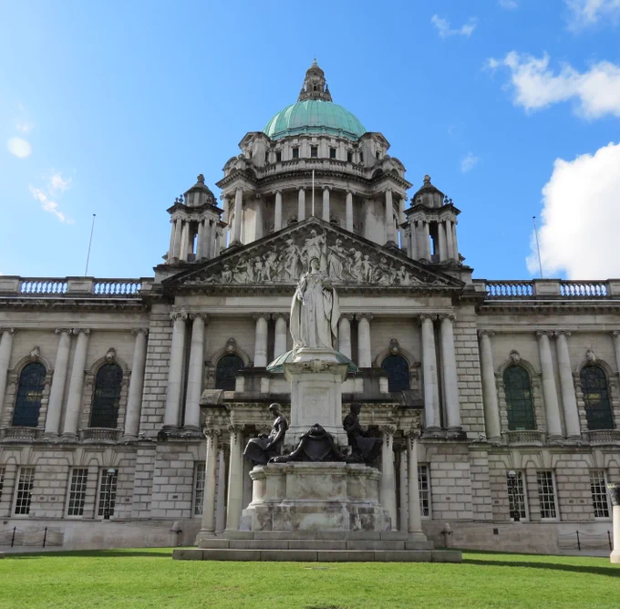The front of Belfast City Hall building under a blue sky with scattered clouds 
