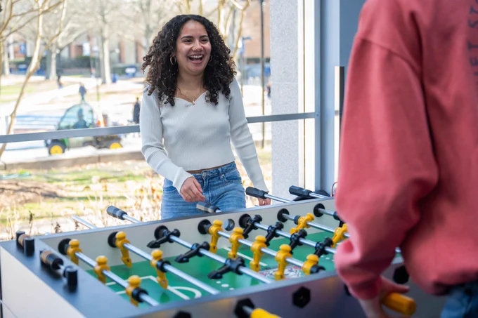 Student laughing while playing foosball