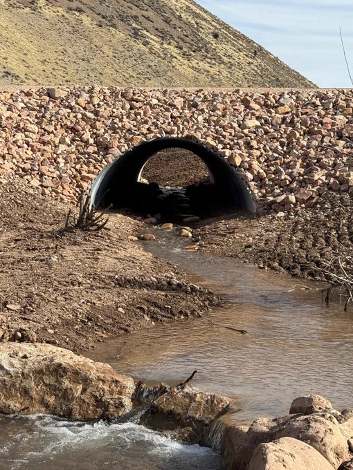 A tunnel with water running through it under a stone bridge.