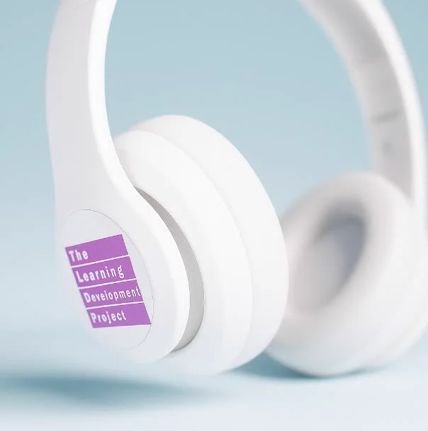 White headphones with The Learning Development Project logo. 