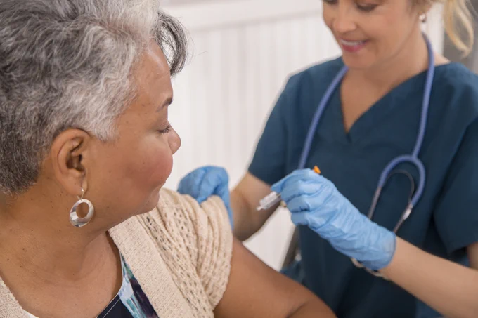 A healthcare worker administering a vaccine to a patient in a clinical setting.