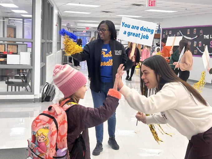 Mornings with Moms volunteers cheer on students as they enter the building.