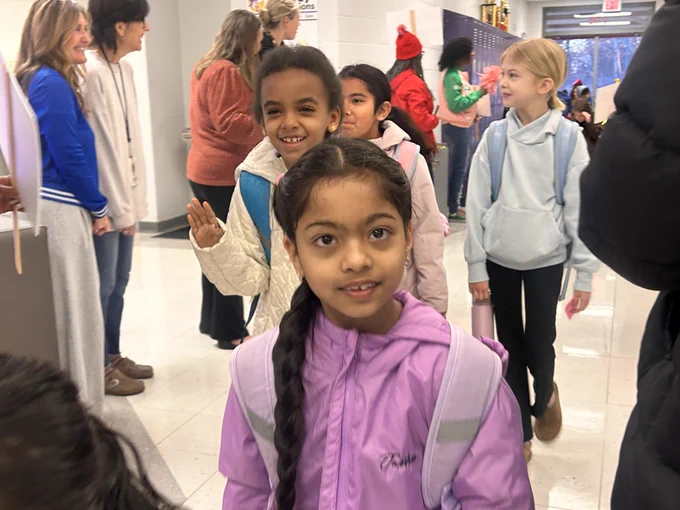Students walk down the hall as Mornings with Moms volunteers cheer.