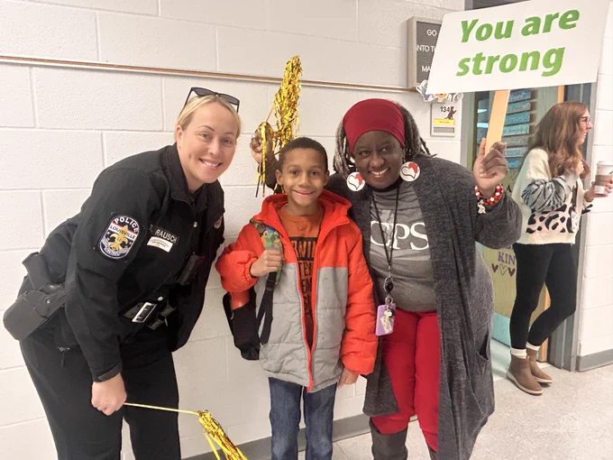 Two adults and a student pose for a picture and smile.