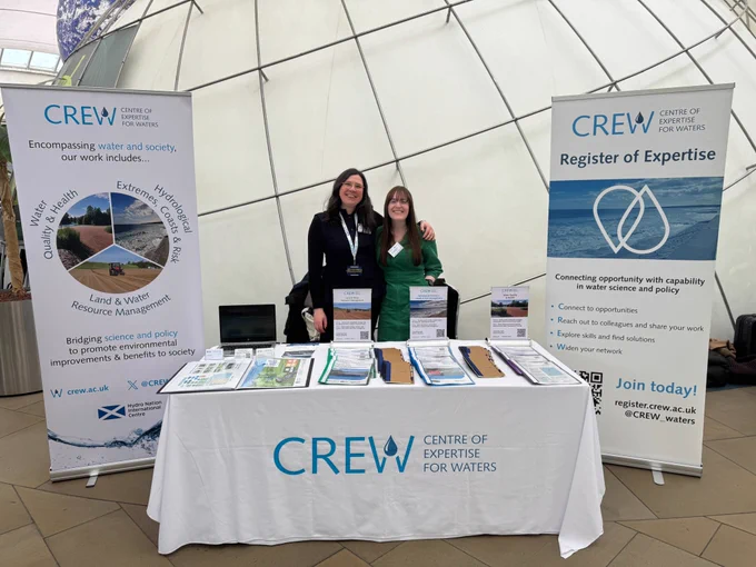 Amy Cooper (Communications and Impact Officer) and Rebekah Burman (Project Manager) behind the CREW stand at the 2025 Verture Flood Resilience Conference.