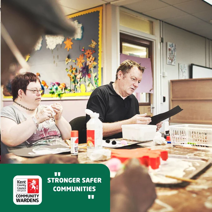 Image shows people sat at a table doing crafting.