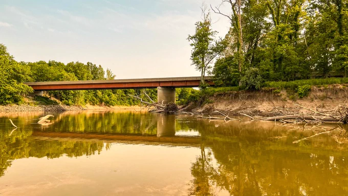 A bridge over the Sangamon River with green-brown water and exposed, dry river banks.