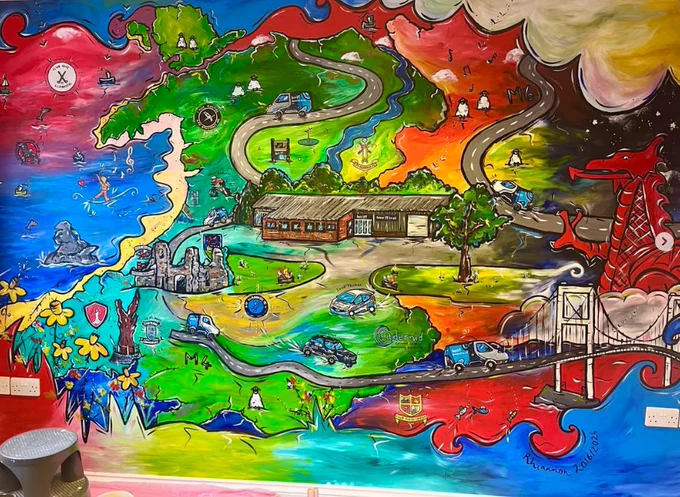 Colourful wall mural at the BCC It office in Newcastle Emlyn, depicting an impressionist map of Wales with local landmarks, roads, and the bcc vans