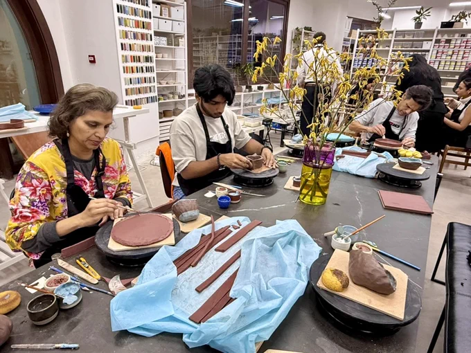 Monica Rao, Dr. Rao, and a gentleman work with clay in a ceramics studio.