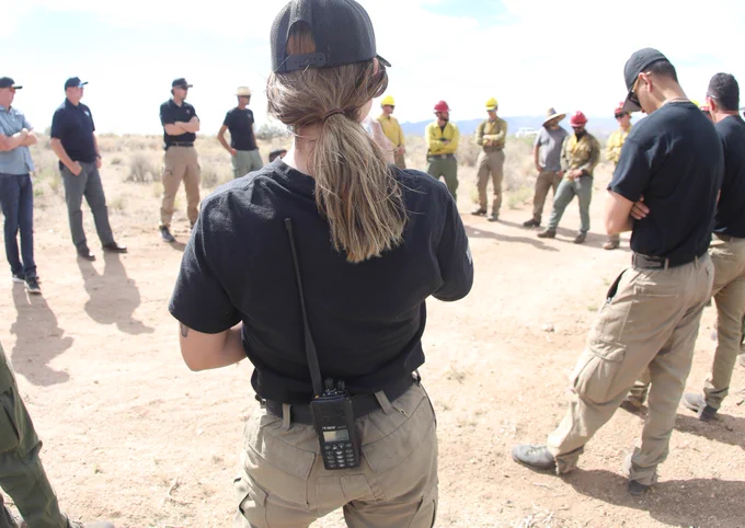 Wildland Firefighters and support personnel brief in a circle. 