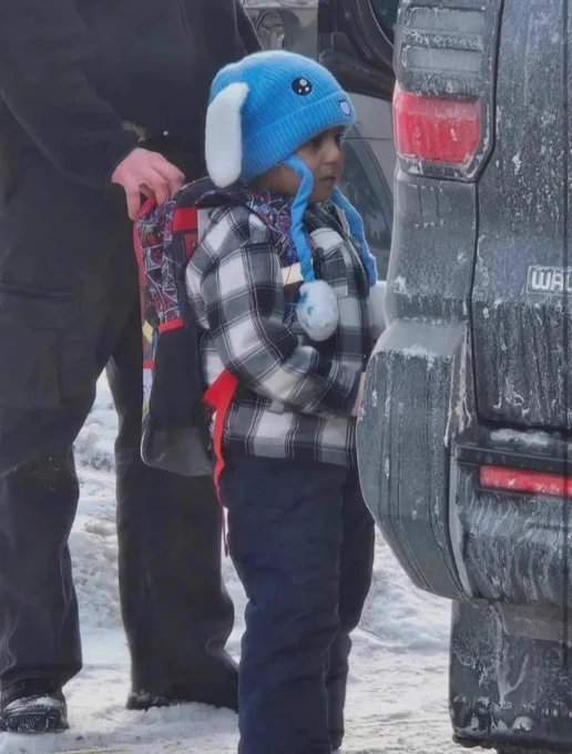 Photo of Liam in a blue winter hat being ushered into a dark vehicle