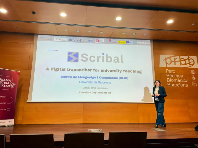 La investigadora Mireia Farrús parla davant d'una gran pantalla on s'hi llegeix, en anglès, "SCRIBAL, un transcriptor digital per l'ensenyament universitari"