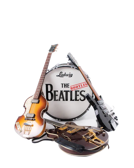 Three guitars resting against a kick drum. The drum has 'The Bootleg Beatles' printed onto it.