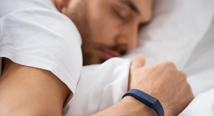Individual lying down asleep with an activity tracker on their wrist.