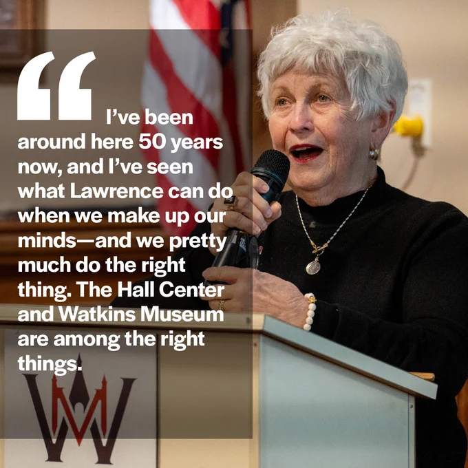 Deanell Tacha speaks at the podium. Text reads, "I've been around here 50 years now, and I've seen what Lawrence can do when we make up our minds--and we pretty much do the right thing. The Hall Center and Watkins Museum are among the right things."