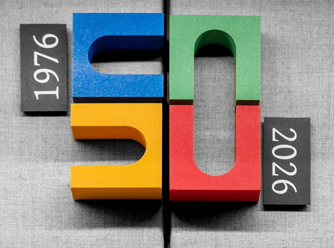 A wooden sculpture of the Hall Center's 50th Anniversary logo hangs on the wall, the dates beside it reading "1976" and "2026"