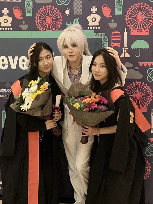 A cross-player posing with two graduates who are each holding a bouquet of flowers.