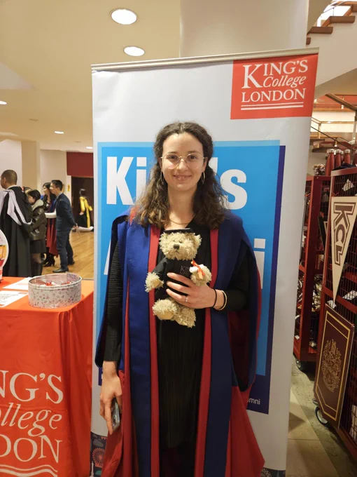 A PhD graduate posing with a King's bear plush that they won from our daily graduation raffle.