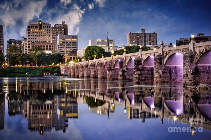 Harrisburg, the capital city of Pennsylvania. is a lovely town. The picturesque Market Street Bridge is shown here spanning the waters of the Susquehanna River. This postcard-type photograph was taken in late afternoon, and the reflection of the blue sky and bridge in the water was stunning. This artwork is from the Fine Art Gallery of Shelia Hunt.