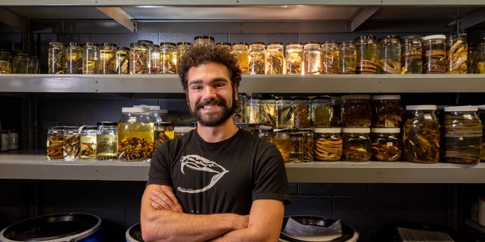 Photo showing Greg Pandelis, ARDRC collections manager, with jars containing snake and lizard specimens at the ARDRC.