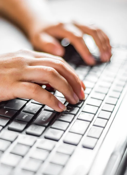 Hands typing on a laptop keyboard.