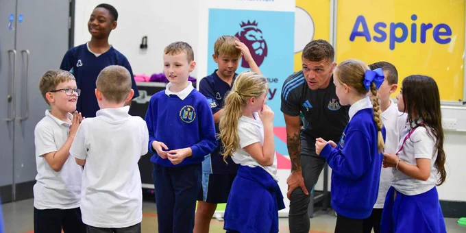 A group of children interacting with an adult at a Newcastle United Foundation event in a colourful indoor space.