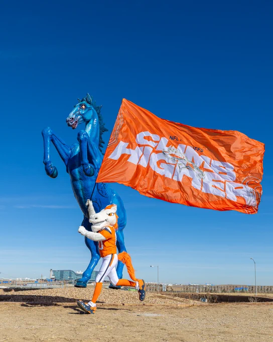 Broncos mascot Miles running with a banner that says \u201CClimb Higher\u201D in front of Mustang