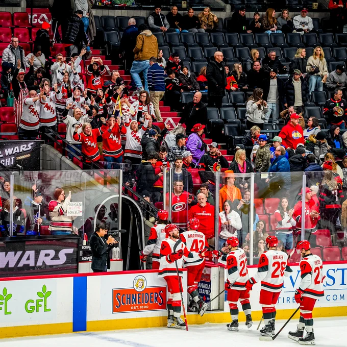 Photo of the team walking off the ice after the win with Canes' fans cheering for them