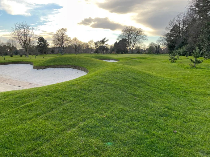 A golf course featuring a green and a sand bunker in the foreground