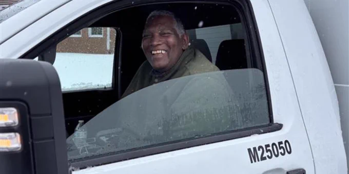 White Montgomery County Public Schools truck parked outside with a driver visible through the window on a snowy day.