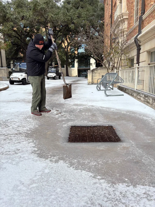 Employee with shovel mitigating ice on IT Austin’s campus