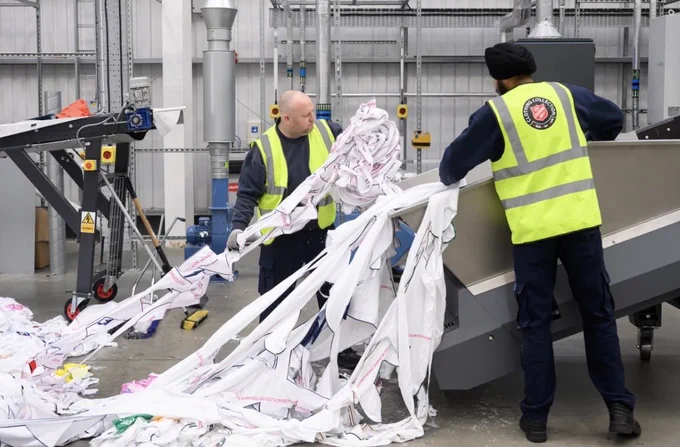 Workers load unwanted polyester textiles into the Project Re:Claim system, the first commercial-scale polyester recycling plant of its kind, last year in Kettering, England. Leon Neal/Getty Images