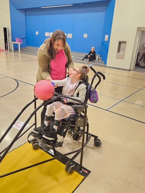 CRAEA staff working helping a student in gym class