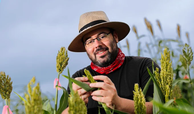 James Schnable looks to the camera while examining sorghum