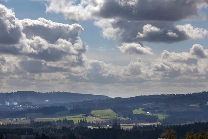 An image of an open field with clouds coming in. 